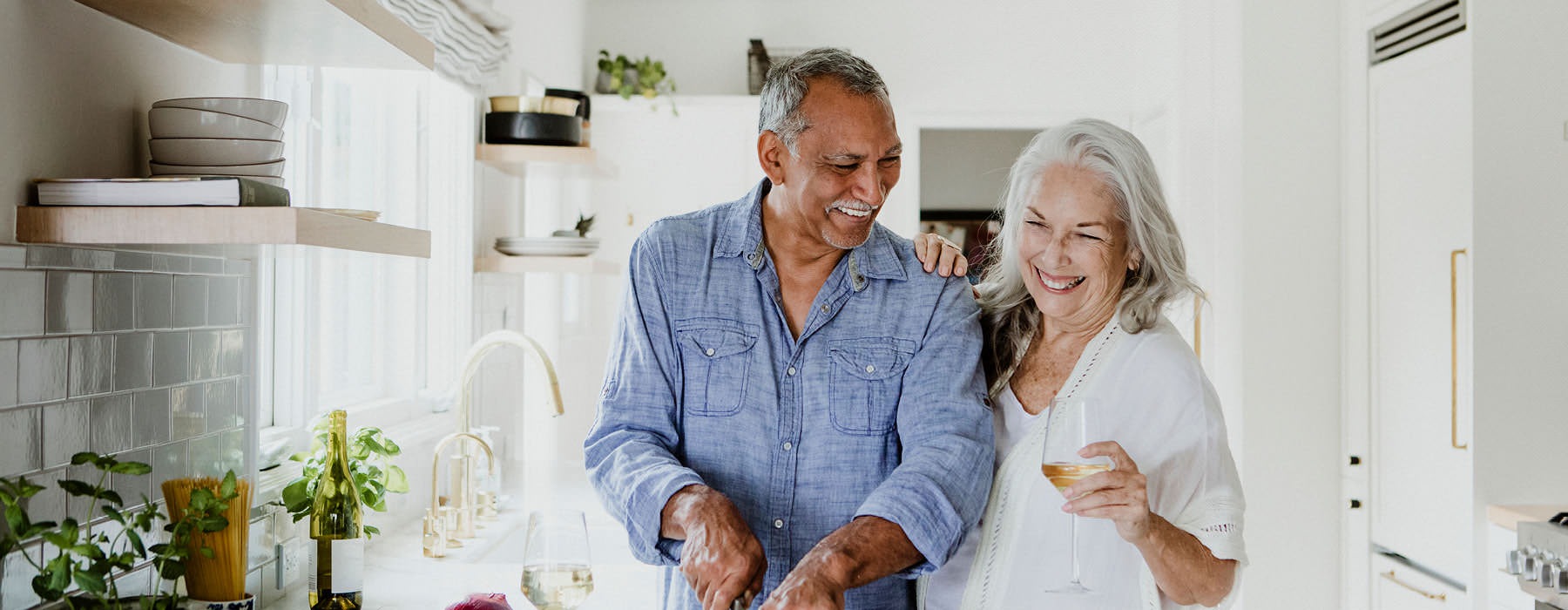 older couple happily cook together in kitchen
